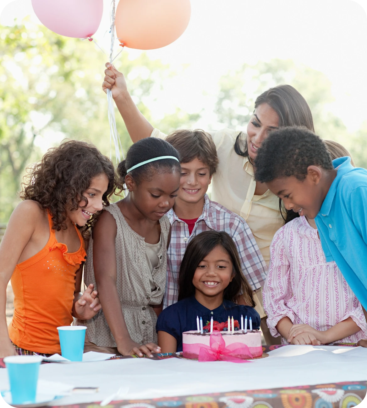 Children celebrating birthday with cake outdoors